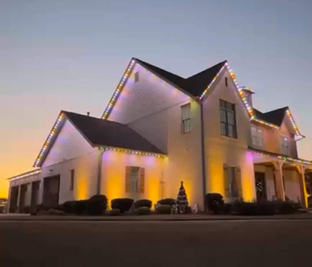 White two-story home in Cincinnati, OH at sunset with multicolor permanent LED lighting on the rooflines and warm uplighting on the walls